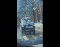 Black car drives with bunch of snow on it