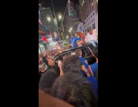 Crowd blocks road guy stands car roof