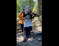 Person in chicken costume plays violin at park