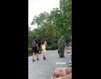 Person in grass costume talks to people at park 