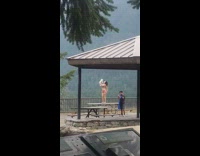 Lady stands on park table to pose with dog 