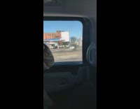 Guy carries broken car parts down sidewalk 