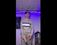 Guy in grey outfit in room apologizing to family after shaving cat 