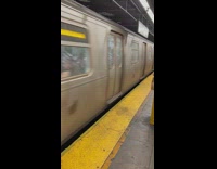 Guy in pink and booty shorts waits for train 