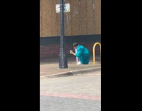 Guy blue graduation gown cash squats sidewalk 