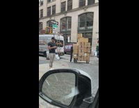 Guy tries to push tall cart of stacked boxes 
