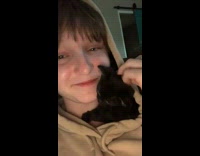 Girl with black kitten in sweater hood 