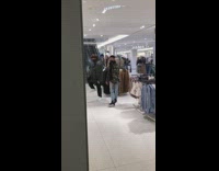 Two guys dance inside mall cloth racks