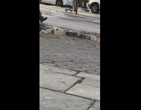 old woman bent over pushing black cart