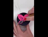 Decorating pink flower onto black cupcake