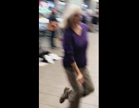 older woman in purple dances to music in subway station