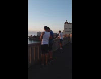 White shirt guy hands on railing beach 