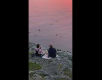 Woman hold grapes over mouth shore sunset