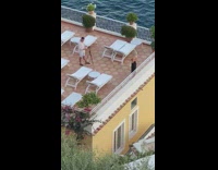 Woman in black dress poses with a wine glass on the rooftop