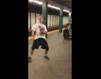 man in white shirt dances to music from violin in subway station