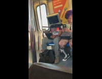Guy with TV set on top of his head uses tablet on the subway