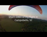 Man with parachute and motor behind glides at sunset