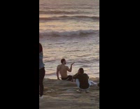 Shirtless man cliff posing hand up holding sun angle 