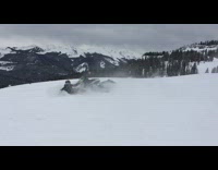 Guy falls off green snowmobile snow hill