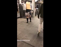 Woman goes through subway turnstiles with a cardboard box on her head