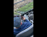 Man using dating apps while bored at football game 
