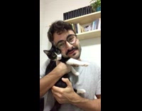 Guy holds meowing cat up to face 