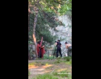 Man holds lightsaber filming video at park