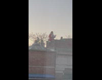 Santa claus sitting on roof clapping hands