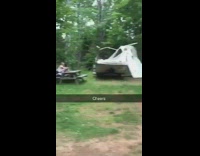 Couple makes out on bench next to broke trailer home in forest