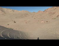 Dirtbiker drives uphill in desert, catches air, and lands 