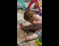 Baby girl tries to eat cookie on onesie 
