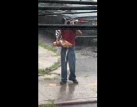 Man hold wet pizza box street rain
