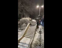 Students rolls a giant snow boulder down the stairs 
