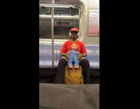 Man red shirt hold chucky doll subway