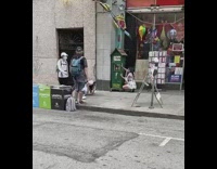 White romper girl squats sidewalk green machine 