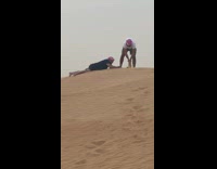 Two men red Keffiyeh lie down desert sand