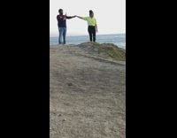 Guy holds hand and photographs girl ocean 