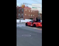 Three people ride red convertible car