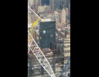 Yellow crane lifts blue porta potty up 