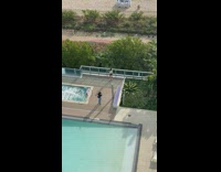 Woman in white top poses poolside while it rains