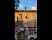 Man on rooftop drop garbage bag on street
