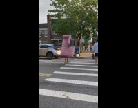 Person carries pink couch across street