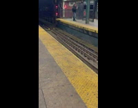 Guy standing on subway train platform practicing with nunchuks 

