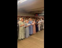 Group holds leaflets sings at train station