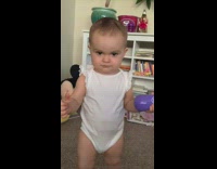 Baby walking around stares at camera and sticks tongue out