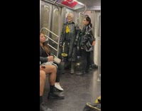 Person wearing bald head mask riding the subway