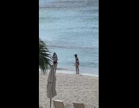 Woman in black bikini with a hat yoga stretch at the beach