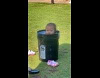 Little girl cools off in water bucket