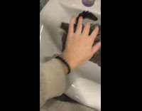 Girl pets cat sitting in bathroom sink