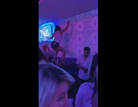 Woman danced on table with man nearby on his phone